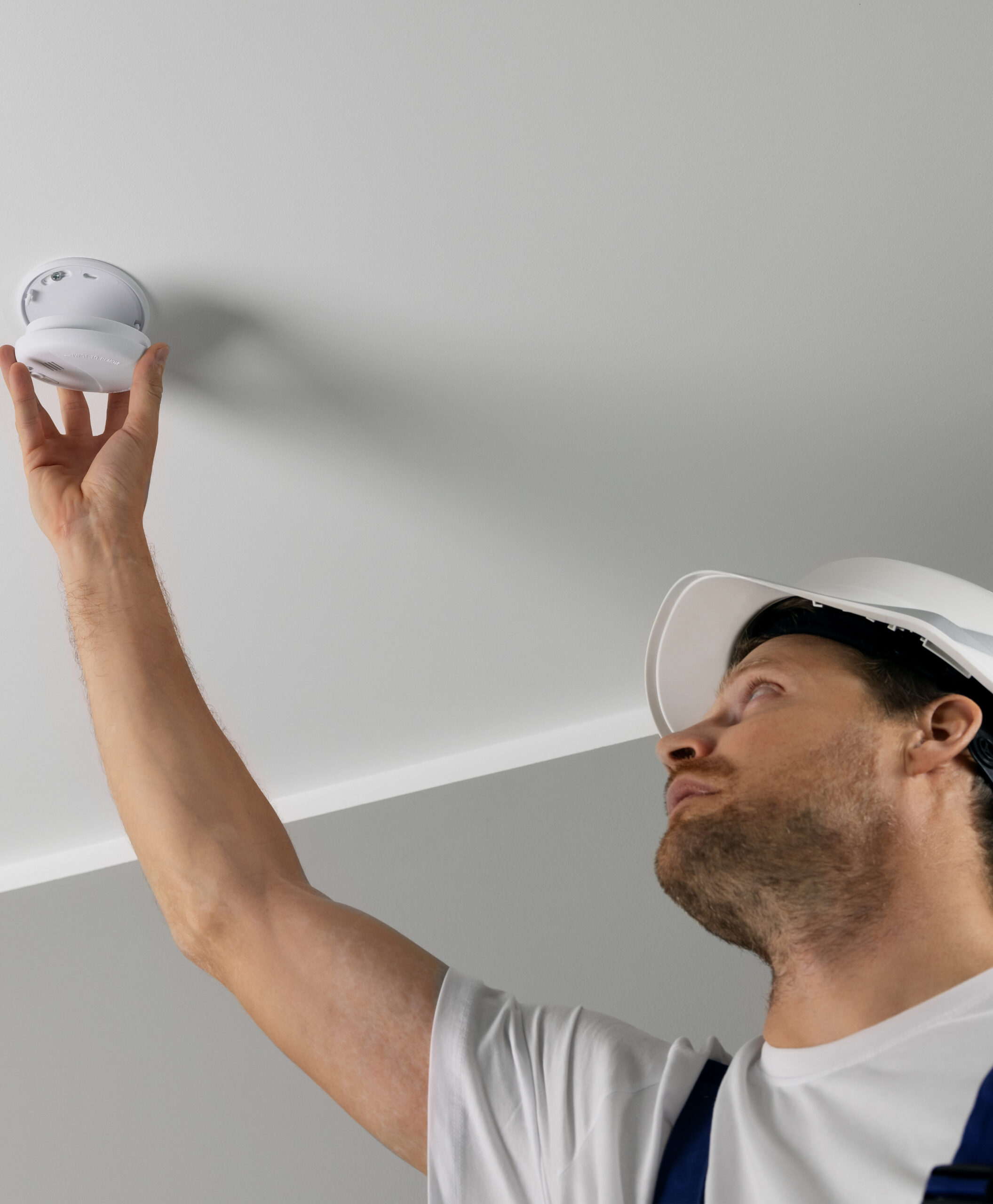 fire safety engineer installing photoelectric smoke detector on house ceiling. home security and fire alarm system